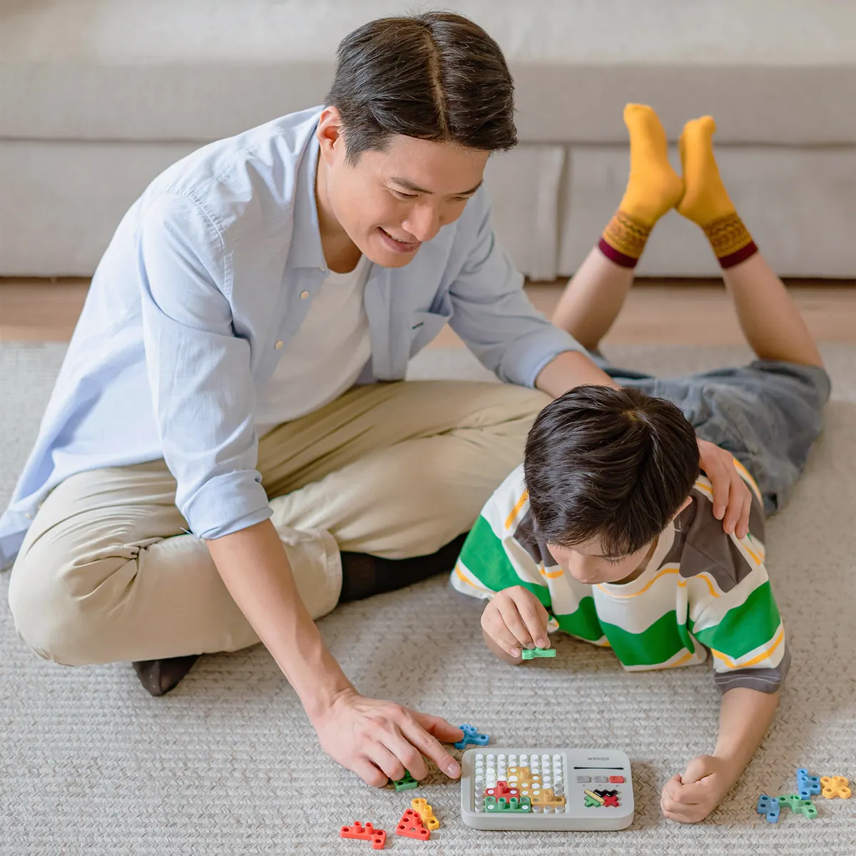 Papá e hijo jugando al Super Blocks en el piso